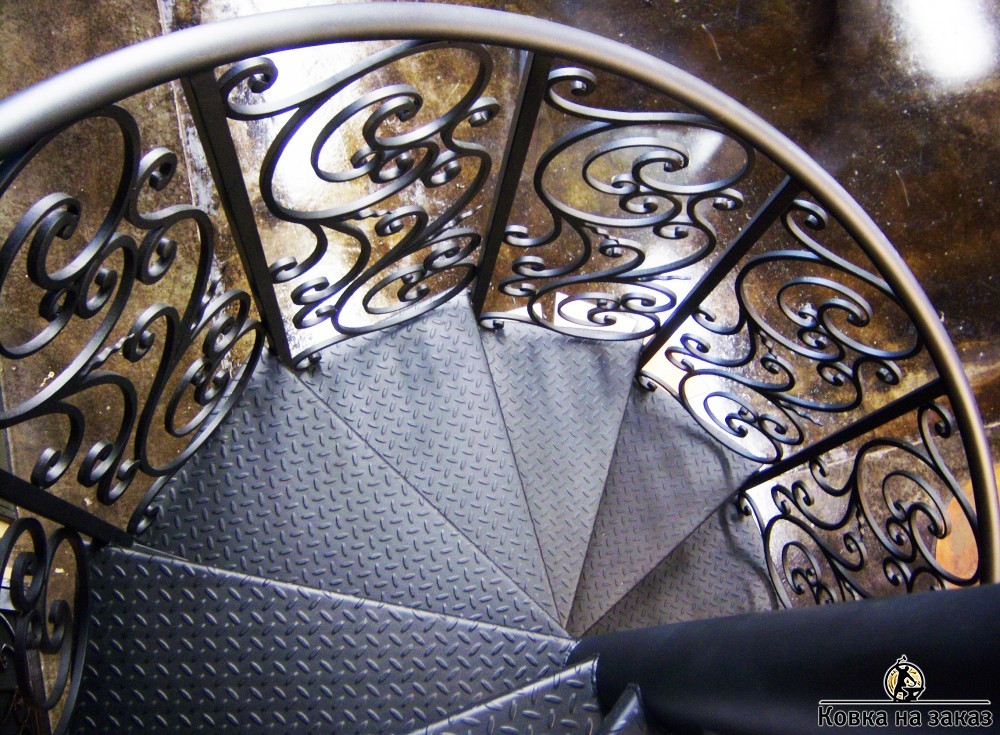 Винтовая лестница с металлическими ступенями и коваными ограждениями