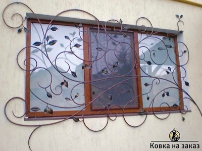 Оконная решетка в виде накладки на стену из кованого под растительный рисунок металла