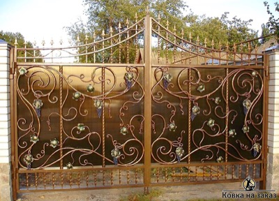 Распашные ворота с торсированными маршем и пиками украшены декоративной витой трубой и виноградной лозой с гроздьями