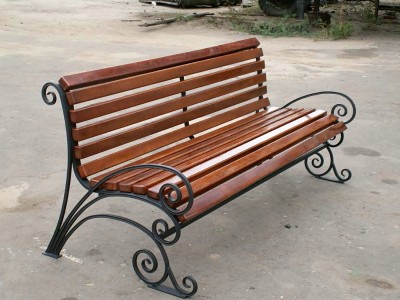 Деревянная садово-парковая скамейка с металлической рамой под сиденьем и большими коваными ножками, переходящими в подлокотники