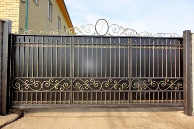 Откатные ворота, закрытые изнутри листовым металлом и&nbsp;украшенные по&nbsp;верхней части коваными вензелями