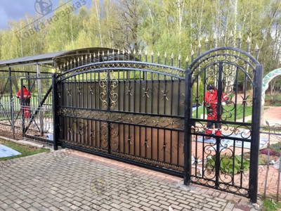 Классические откатные кованые ворота закрыты сотовым поликарбонатом, центральный рисунок ворот повторяется в калитке