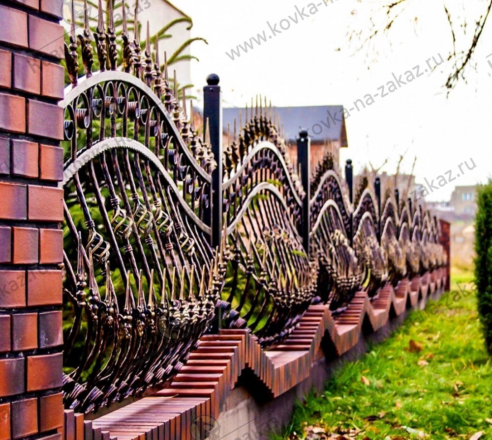 Кованый забор установлен на волнообразное бетонное основание, облицованное кирпичом