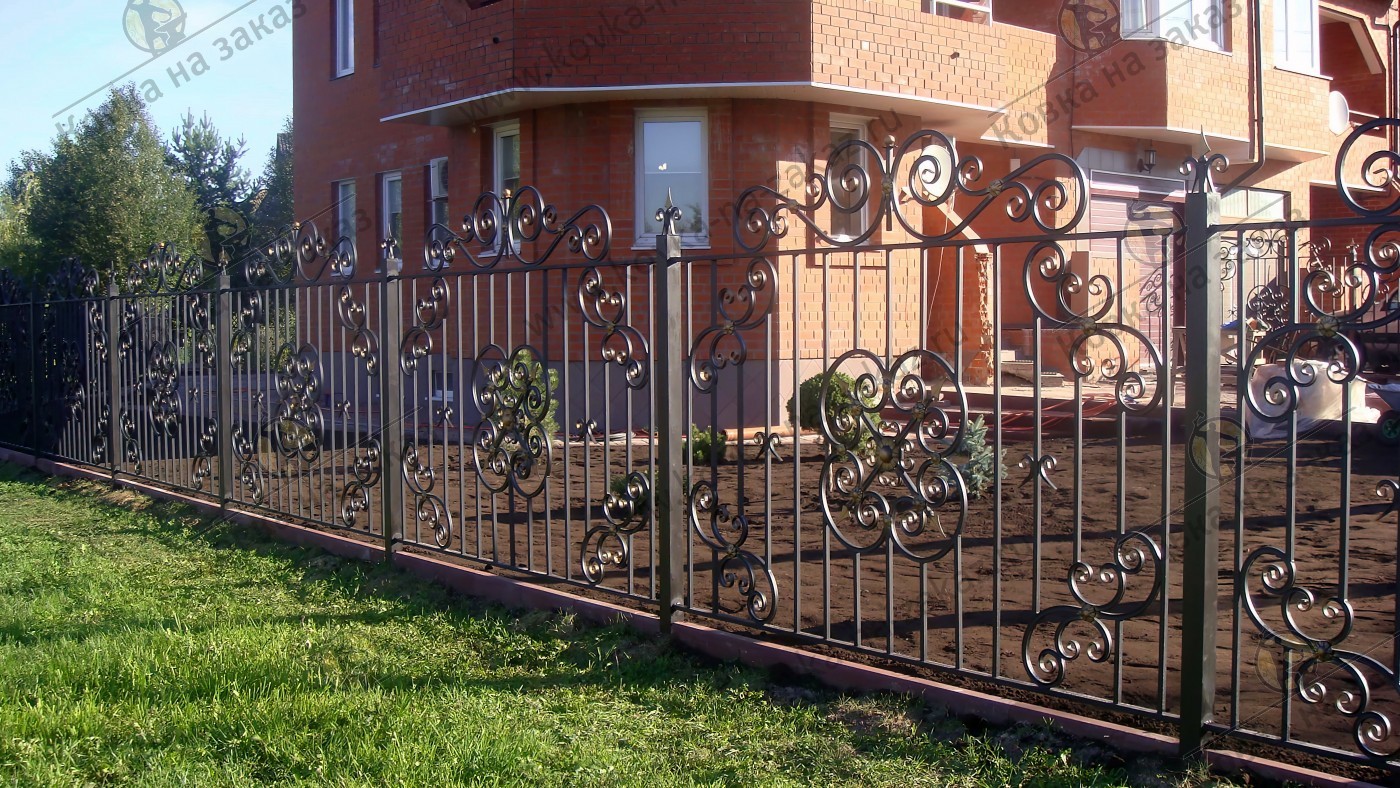 Традиционный кованый забор на&nbsp;металлических столбах для&nbsp;ограждения большой площади вокруг многоэтажного дома